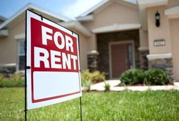 A For Rent sign in the front yard of a rental home