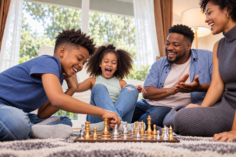 A family laughing together over a chess game at home